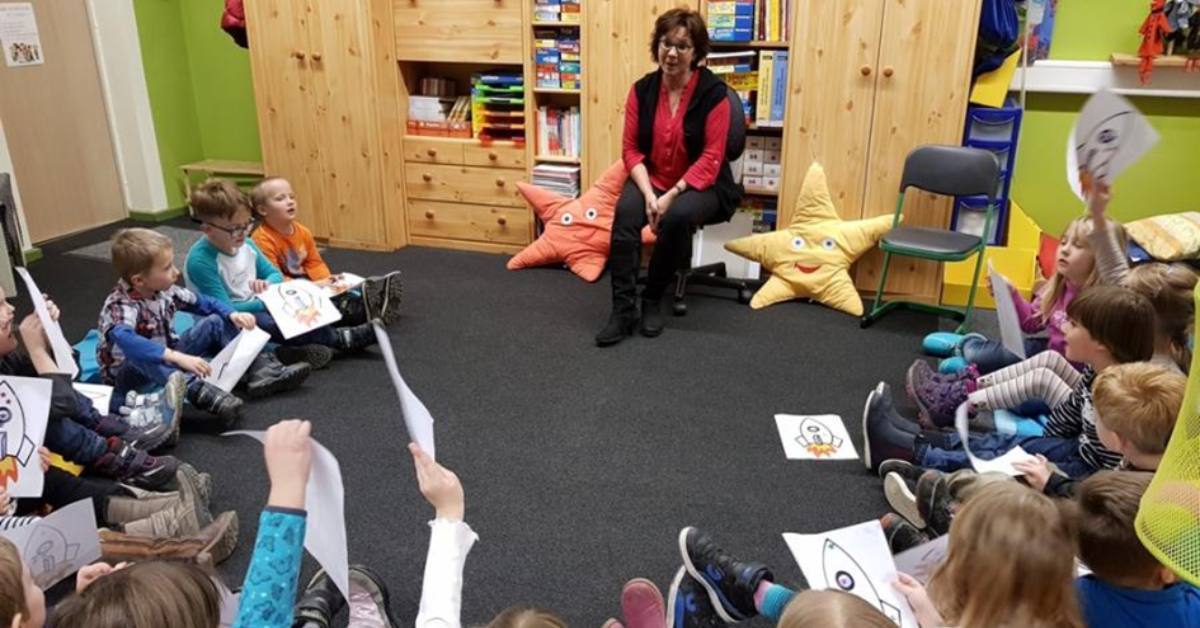 Frau sitzt vor einer Gruppe von Kindern.